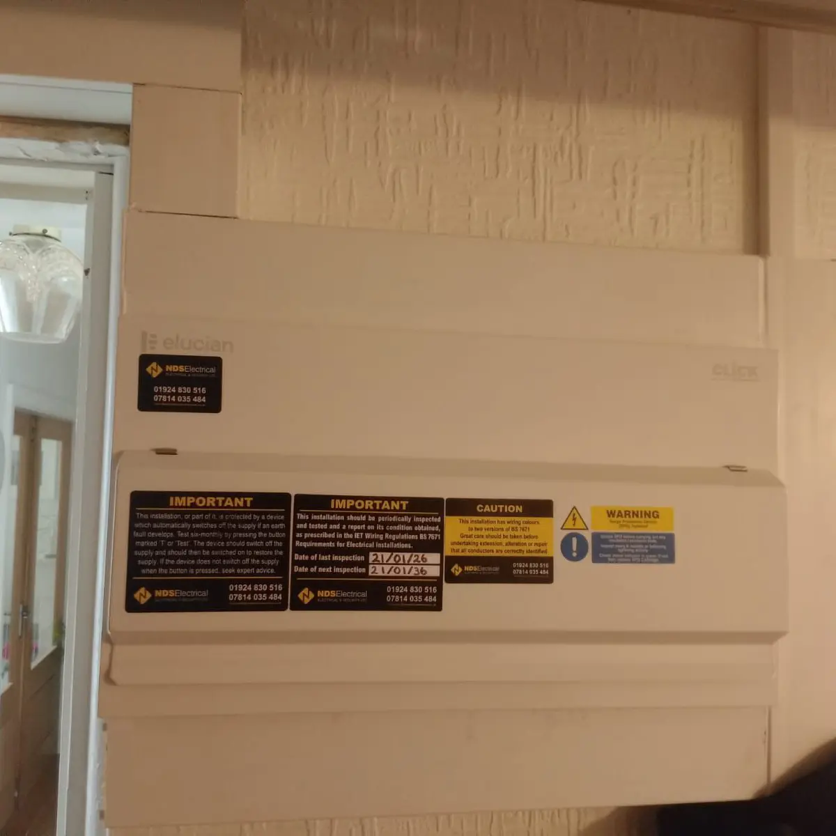 A consumer unit with its inspection notice and next-test date label