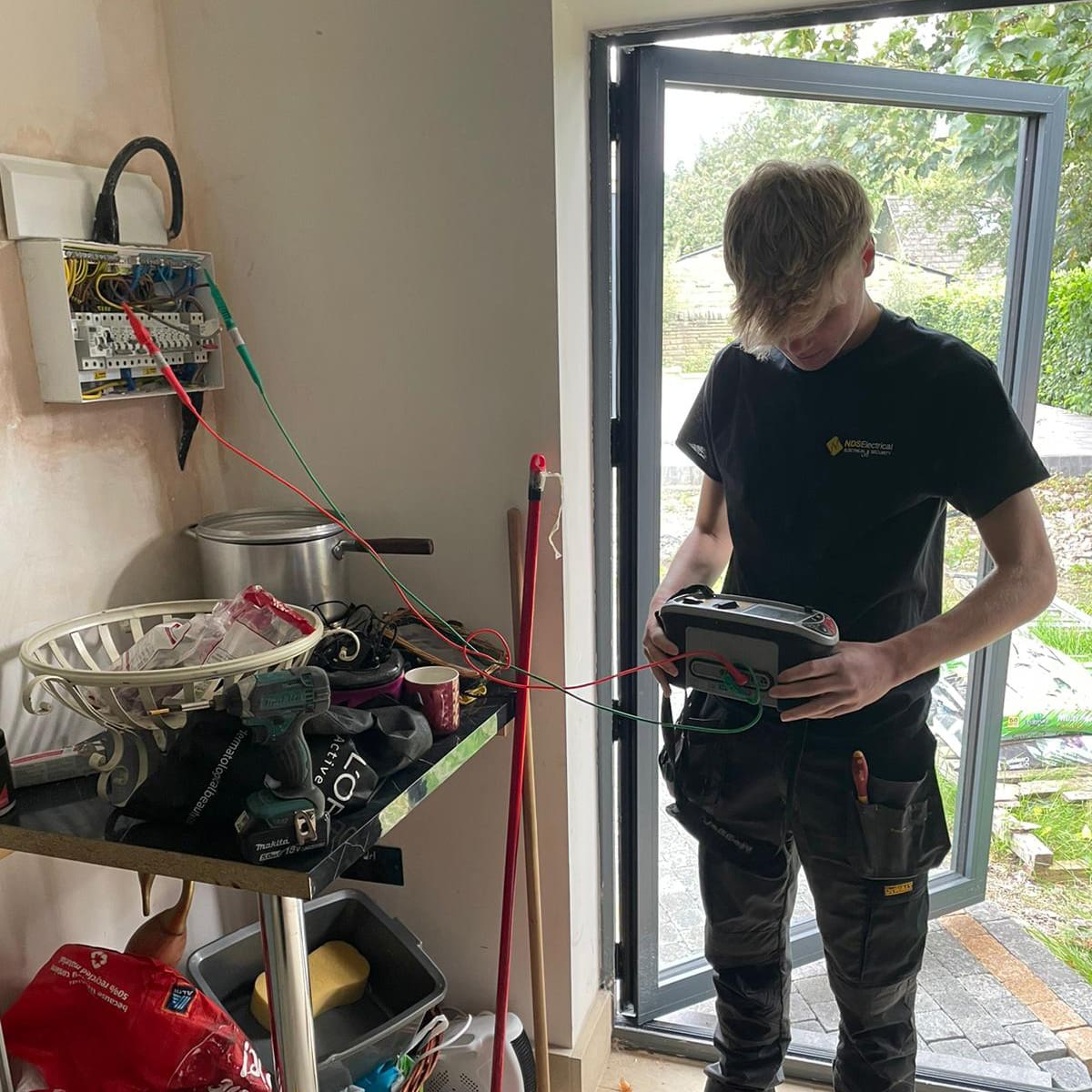 An NDS electrician testing a consumer unit with a multifunction tester in a Horbury kitchen